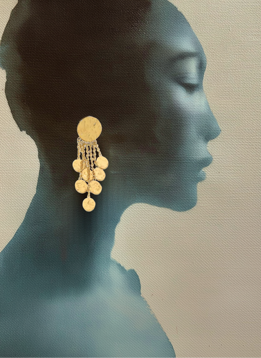 Gold earrings on a silhouette of a woman's profile against a neutral background